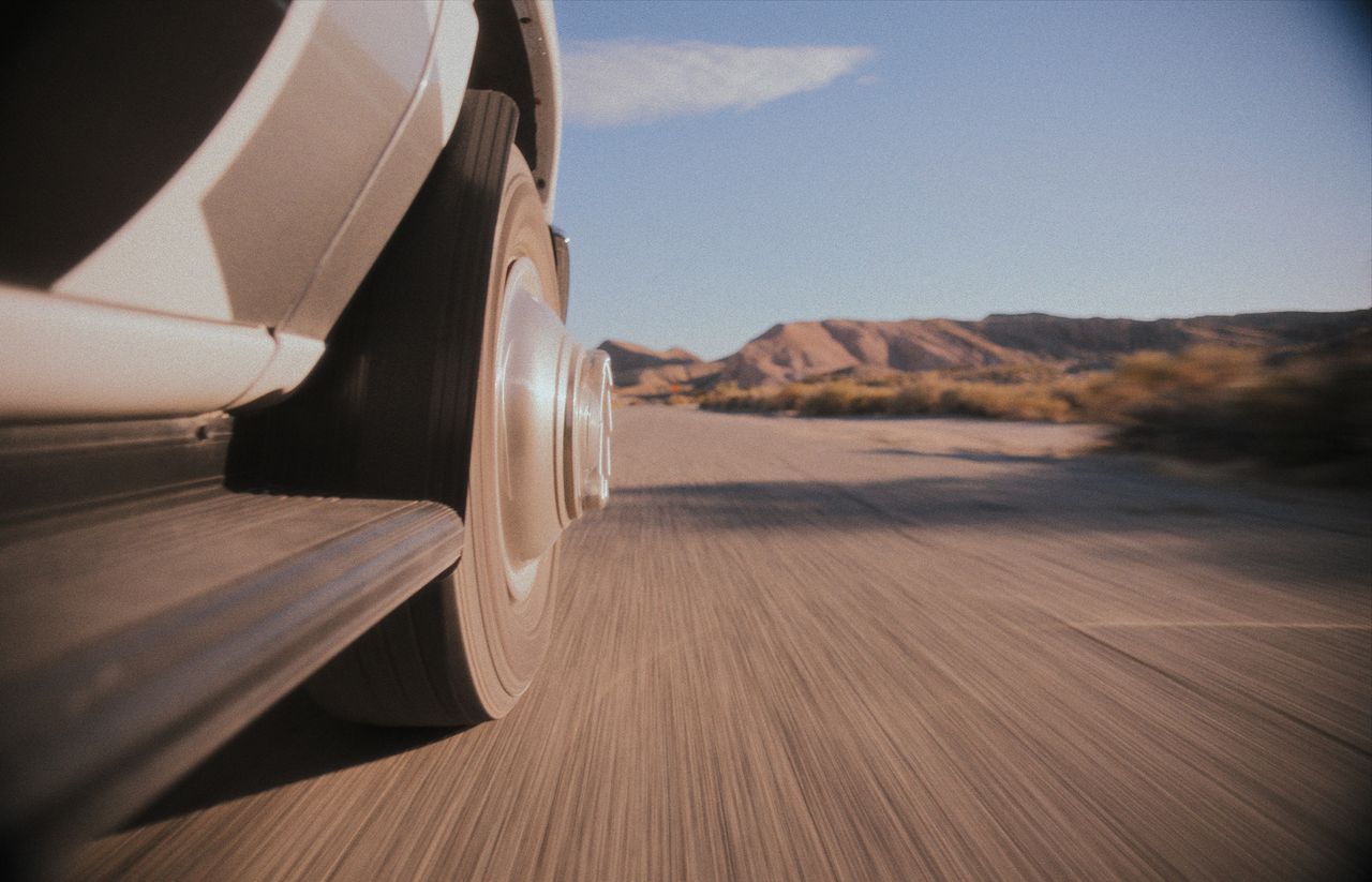 An image of a far away trailer driving down a tree-lined highway