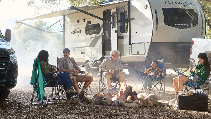Family enjoying near campfire together infront of RV