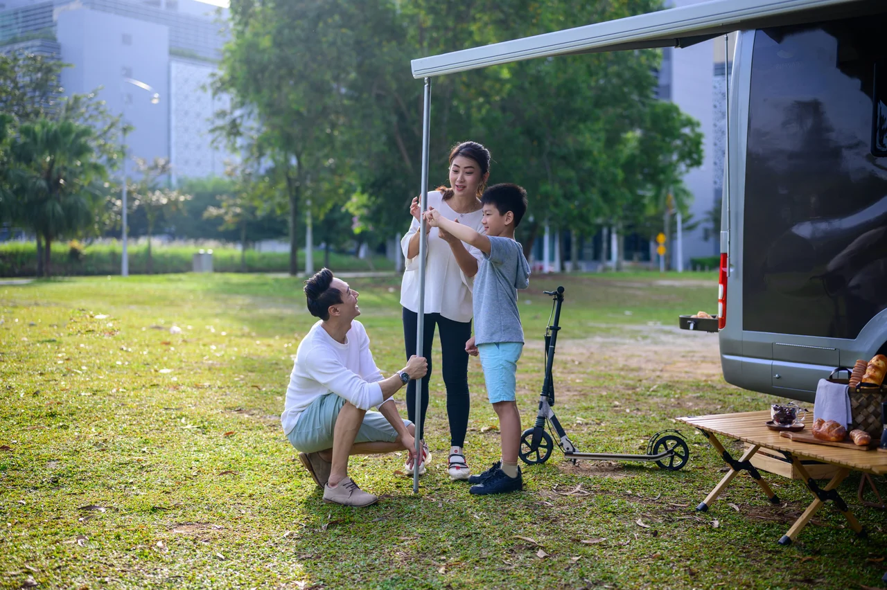 Three people standing beside a bicycle in a park.