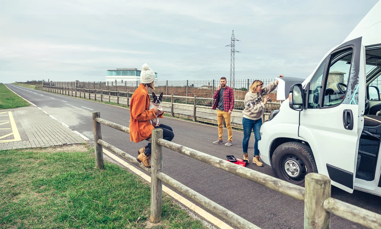 Workers standing beside a service van on a roadside.