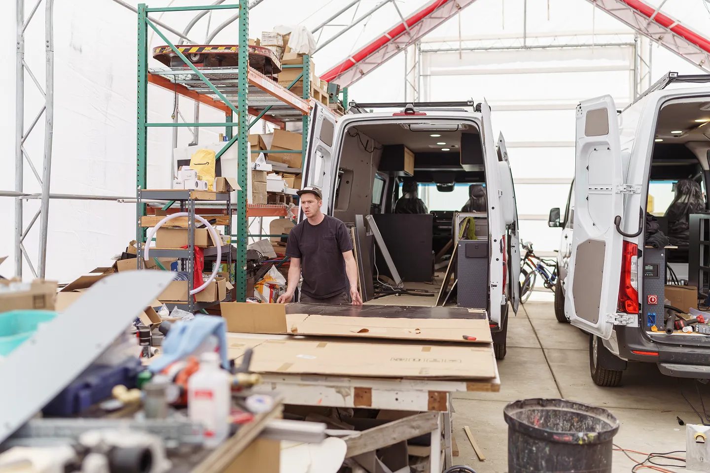 Technician working on a camper van conversion inside an RV remodeling workshop.