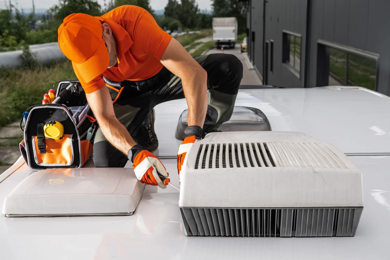 Technician repairing rooftop equipment on an RV.