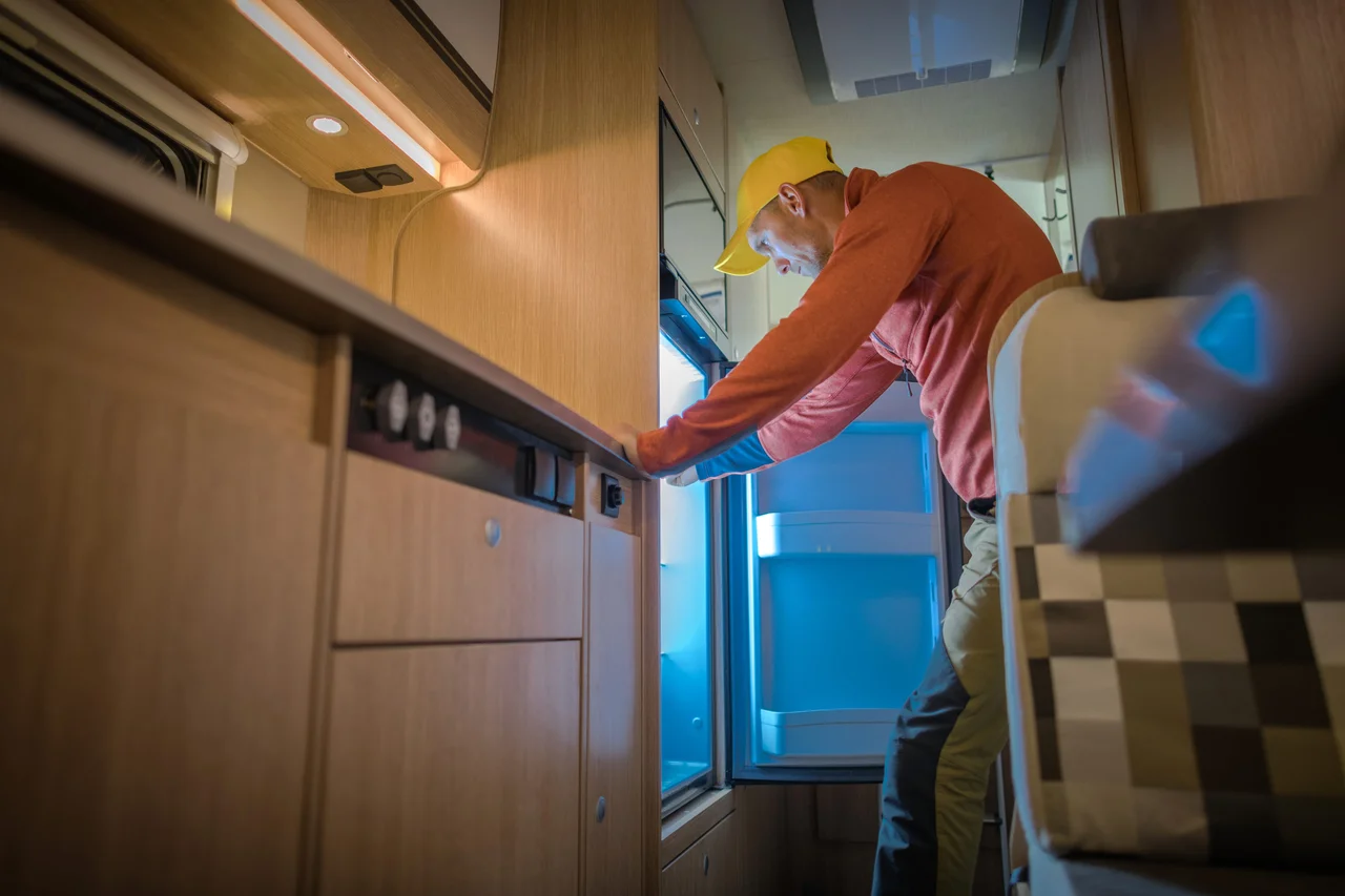 Person inspecting an RV refrigerator with the door open.