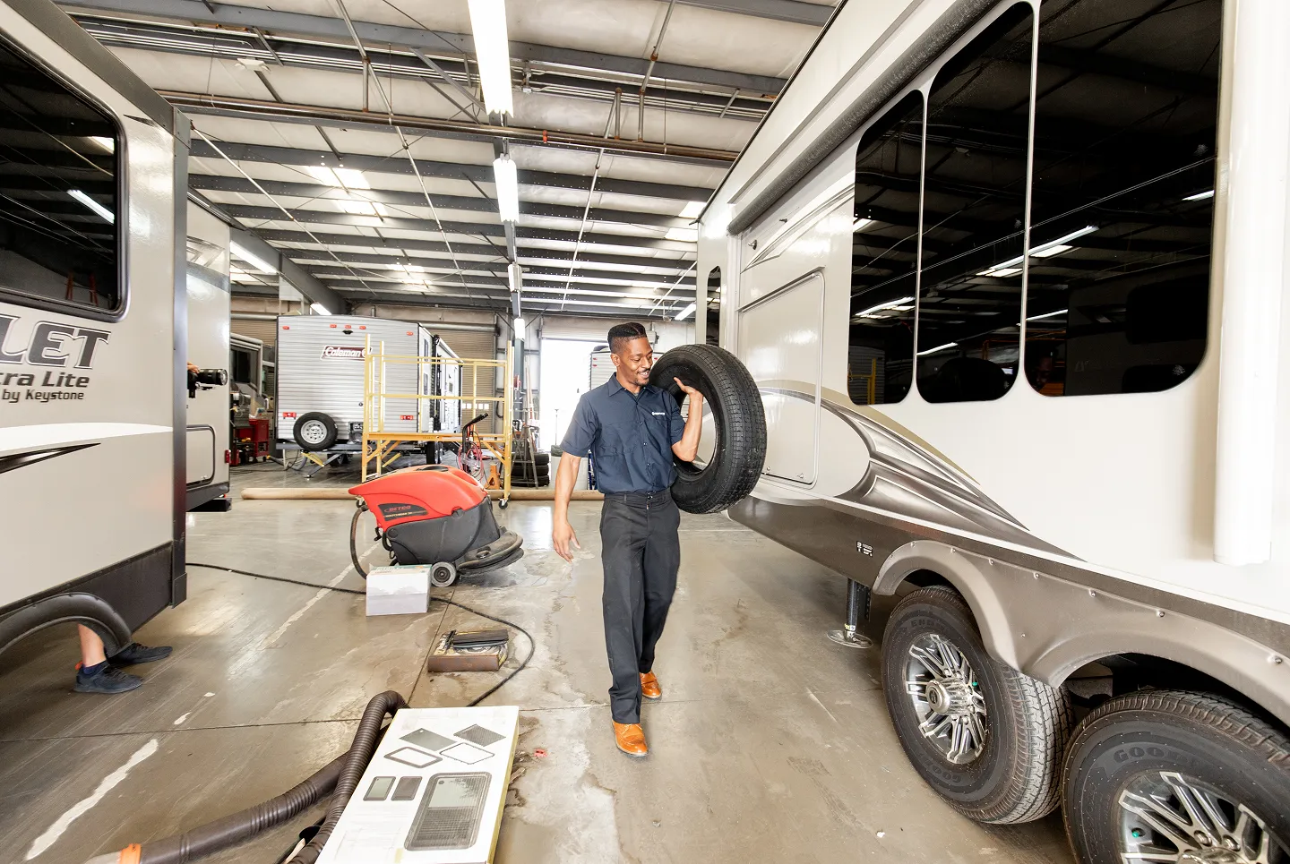 Technician carrying a tire through a service bay.