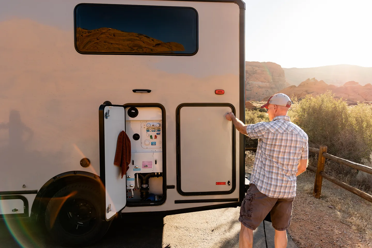 Person accessing the RV freshwater system through an exterior utility compartment.