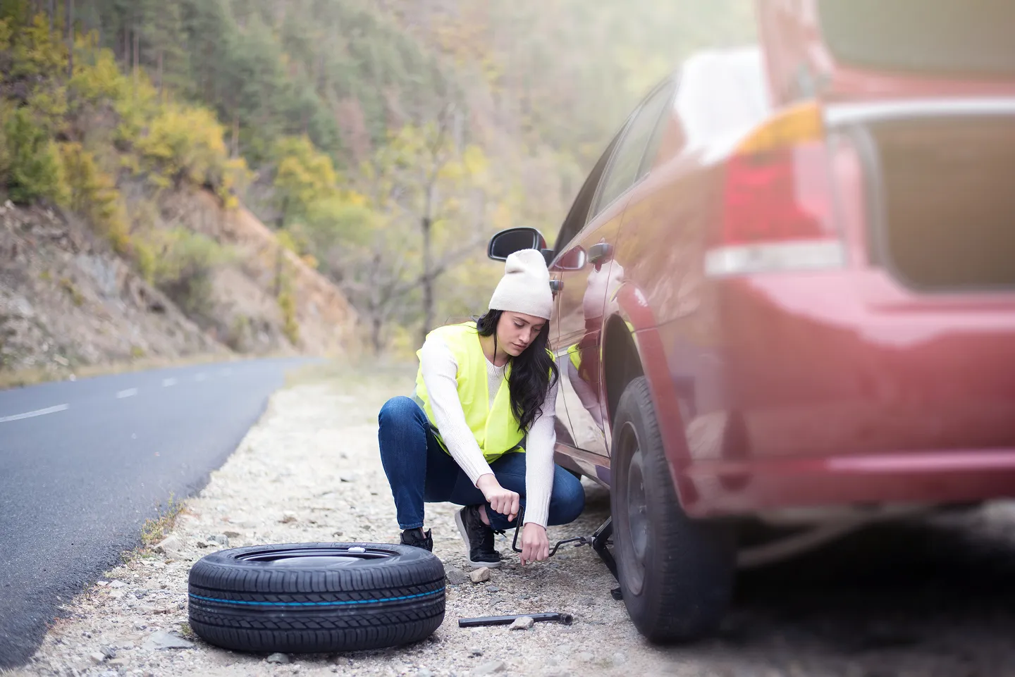 Women changing a tire on the roadside.