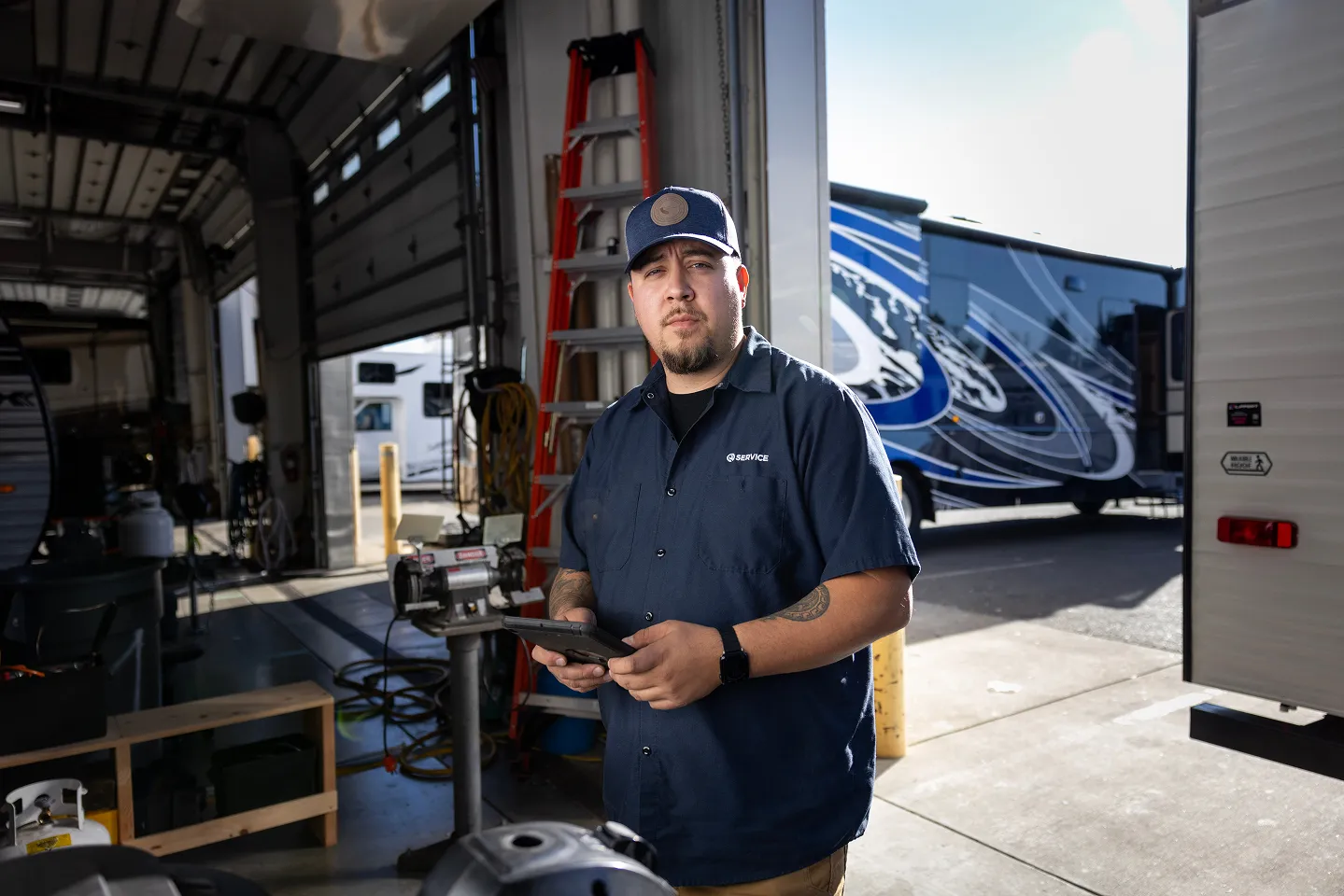 Technician standing in a service bay holding a tablet.