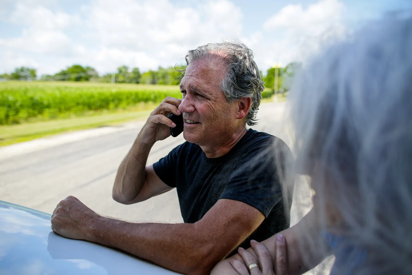Man talking on a phone beside a vehicle.