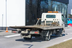White flatbed tow truck with an empty deck waiting curbside, ready for a vehicle recovery