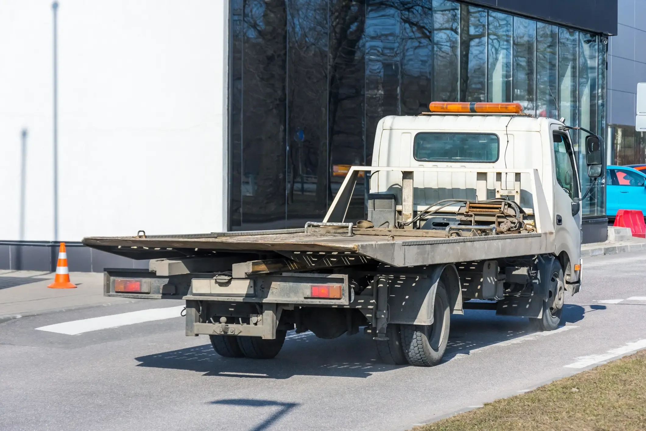 White flatbed tow truck with an empty deck waiting curbside, ready for a vehicle recovery