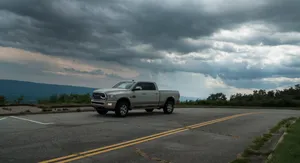 Heavy-duty pickup truck parked at a mountain overlook under dramatic storm clouds