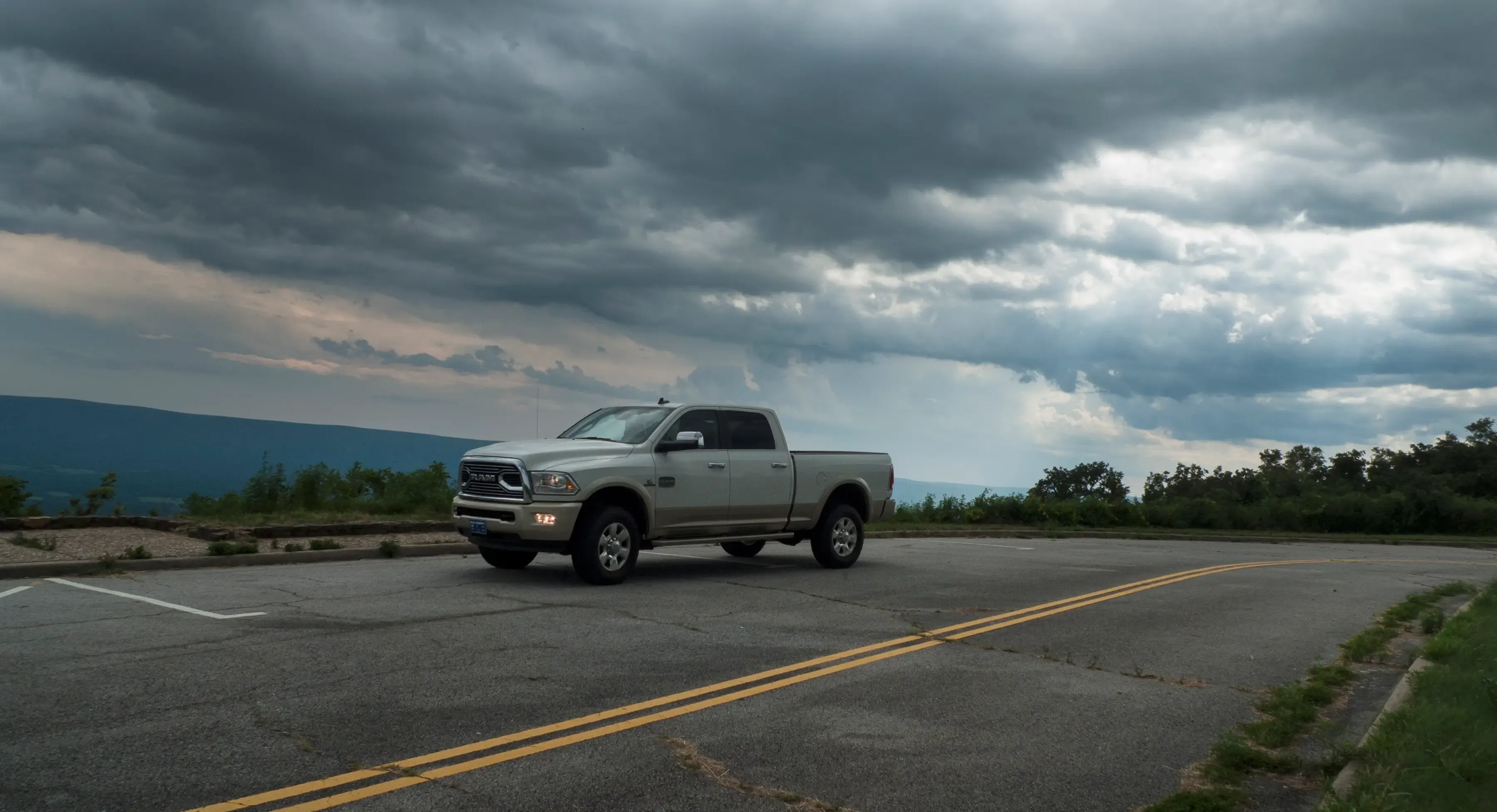 Heavy-duty pickup truck parked at a mountain overlook under dramatic storm clouds