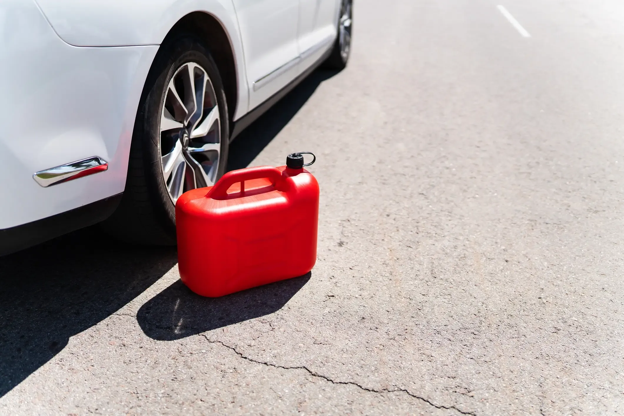 Red gas can sitting beside a stranded white car, ready for an emergency fuel delivery