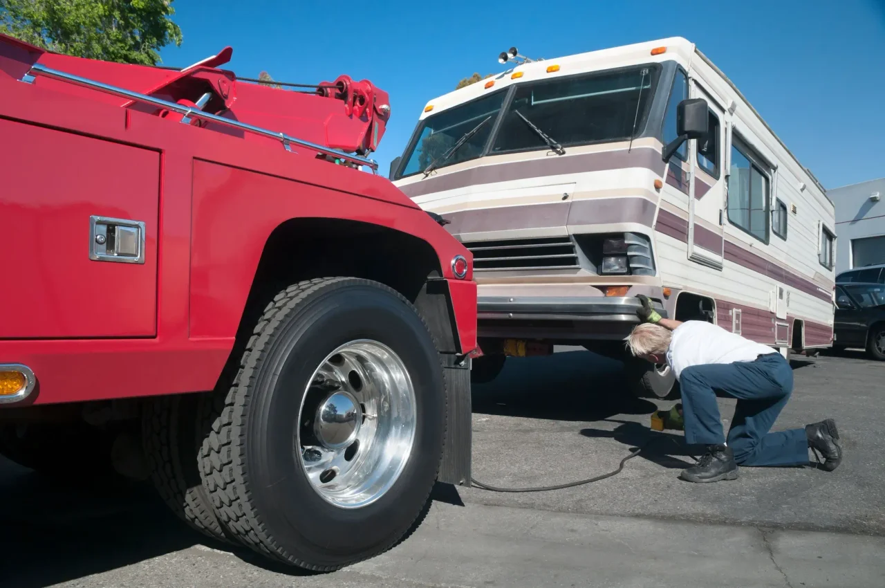 A red tow truck getting ready to tow a broken down RV. 